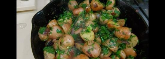 Potatoes in uniforms in a cast-iron frying pan in olive oil with herbs and garlic (+ video)